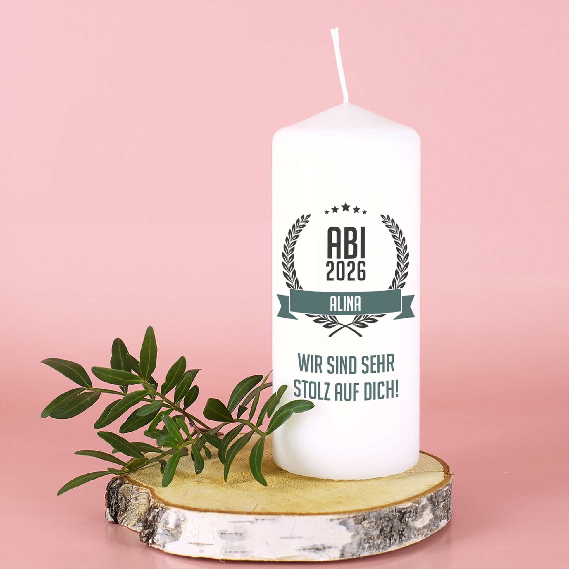 Abitur Kerze mit Name und Glückwunschtext auf Baumscheibe vor rosa Hintergrund