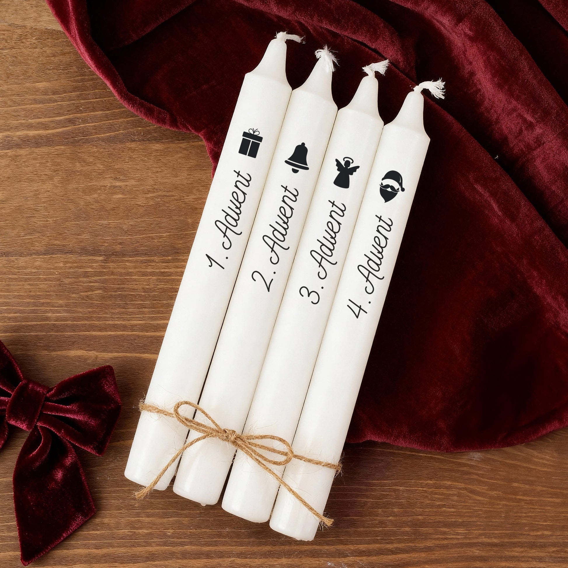 Weihnachtliche Adventskerzen mit Motiv Glocke, Engel und Weihnachtsmann liegend auf Holzuntergrund mit Dekoration