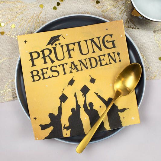 Goldene Servietten Prüfung bestanden auf einem Teller mit goldfarbenem Löffel – Schulabschluss, Abitur oder Studium