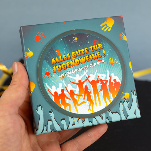 Jugendweihe-Geschenkschachtel in der Hand gehalten, modernes Design mit feiernden Silhouetten