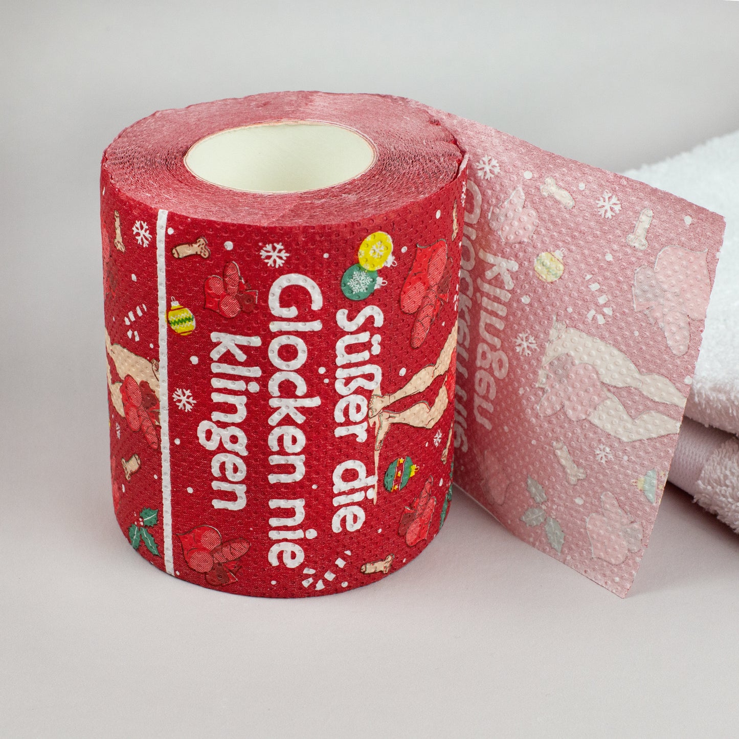 Toilettenpapierrolle Weihnachten rot mit Spruch „Süßer die Glocken nie klingen“ auf weißem Handtuch