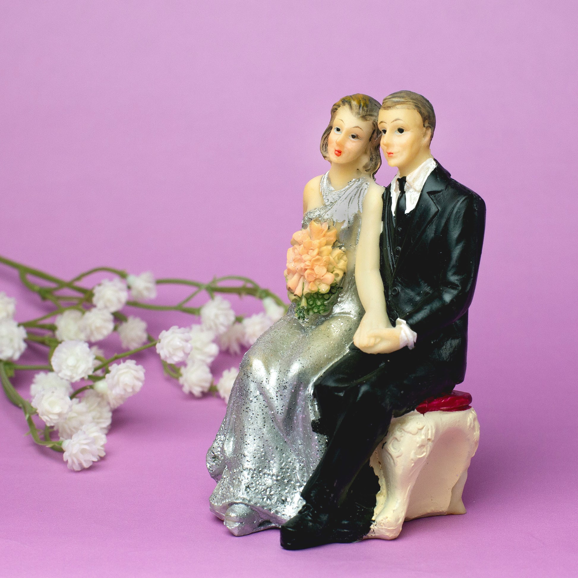 Hochzeitspaar Figur sitzend – Braut im silbernen Kleid mit Blumen und Bräutigam im Anzug