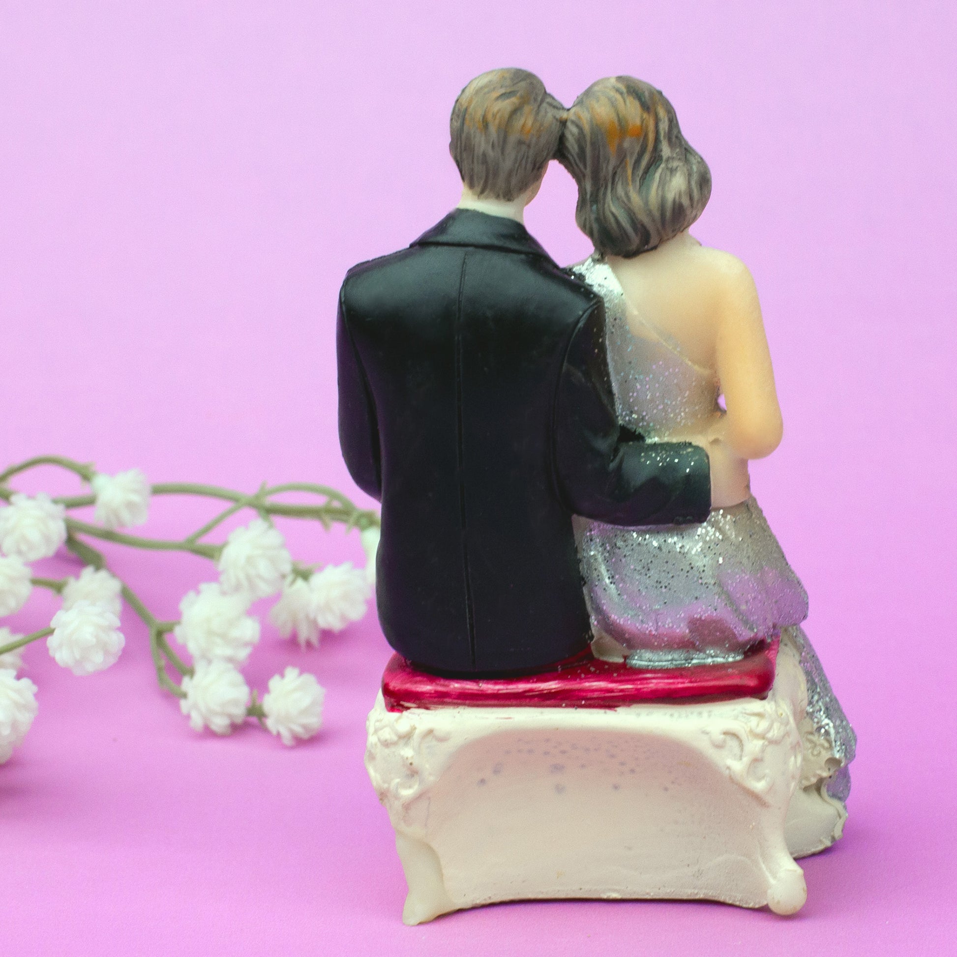 Rückansicht sitzende Hochzeitsfigur – Braut und Bräutigam Arm in Arm auf Bank