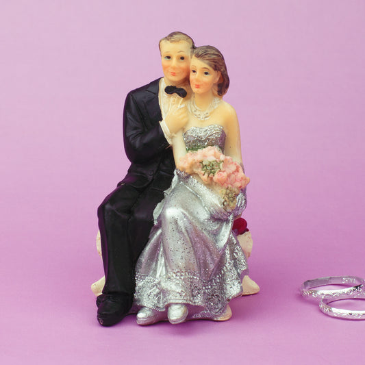 Hochzeitspaar sitzend Figur mit Bräutigam in Anzug und Fliege, Braut im silbernen Kleid mit Blumen
