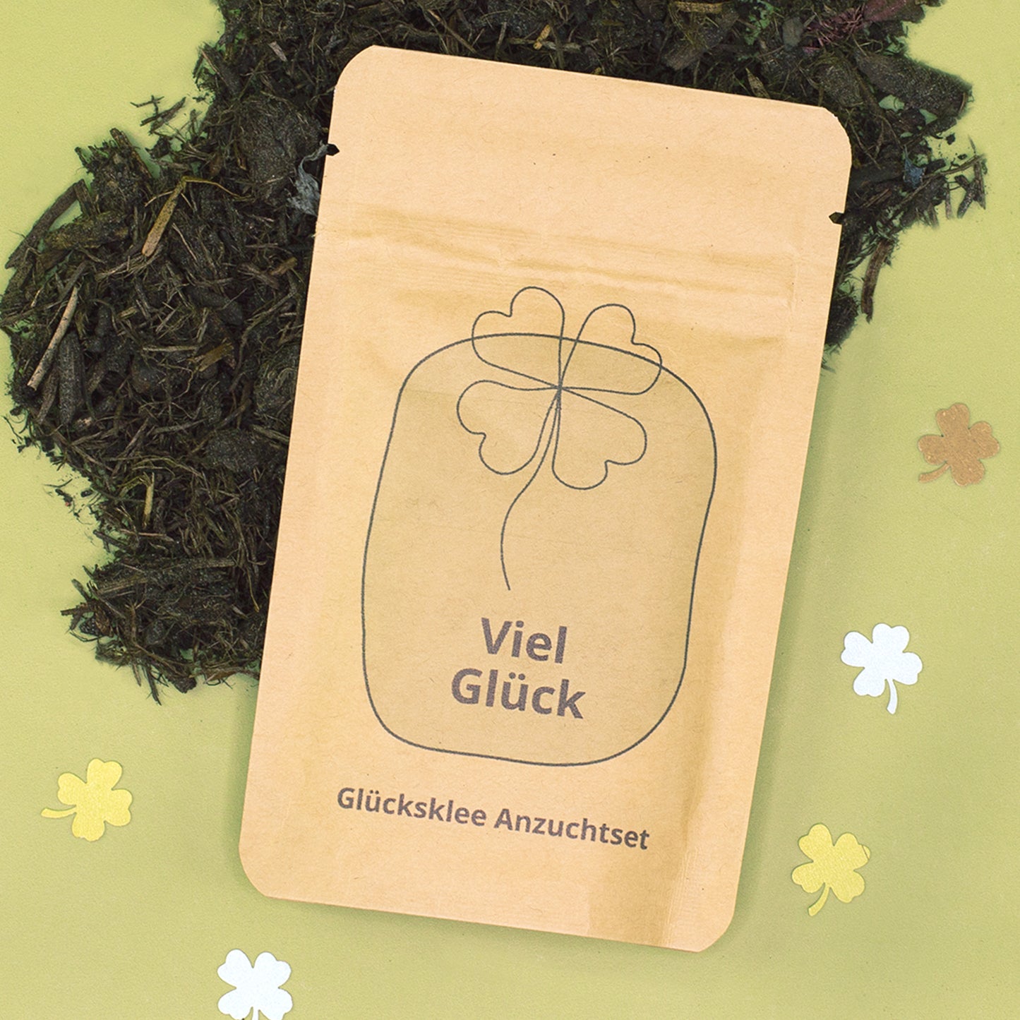 Glücksklee Anzuchtset als kleiner Glücksbringer auf grünem Hintergrund mit Kleeblatt-Deko